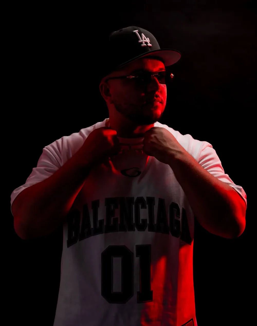Low key studio portrait of DJ Caises with red rim lighting
